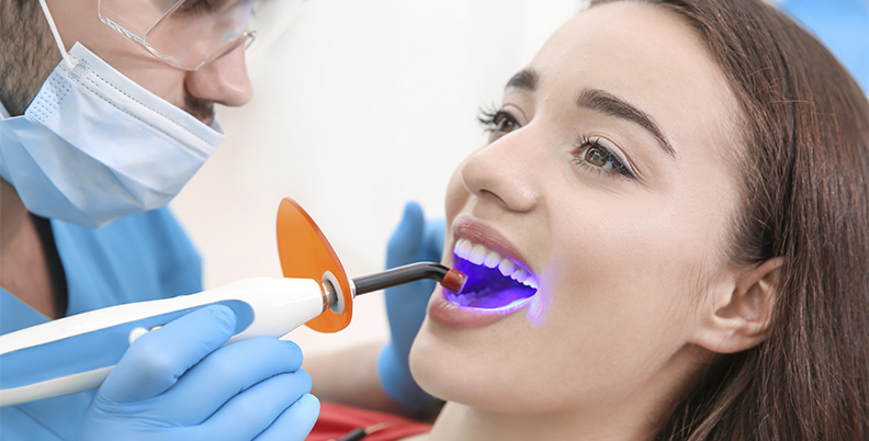 mulher fazendo clareamento dental a laser no dentista
